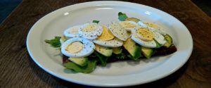 An open sandwich with eggs, avocados and spinach.